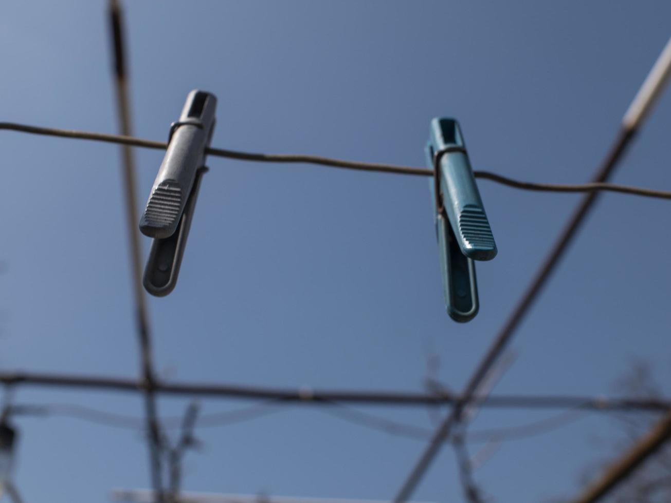 dois prendedores de roupa pendurados em uma corda na rua contra um céu azul foto