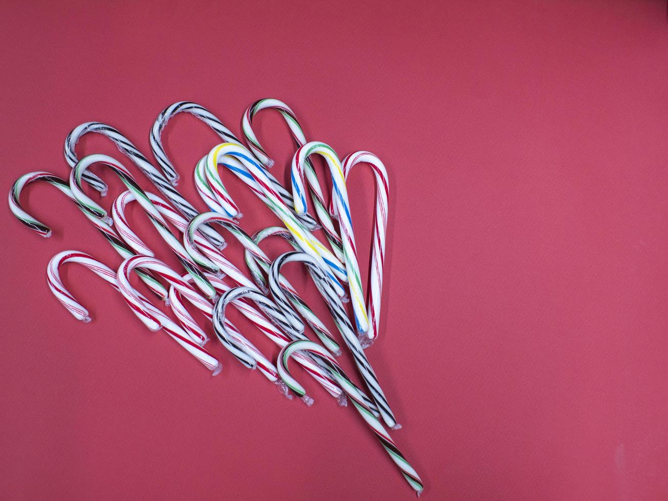 bengala de caramelo de doces de Natal feliz em um fundo rosa foto