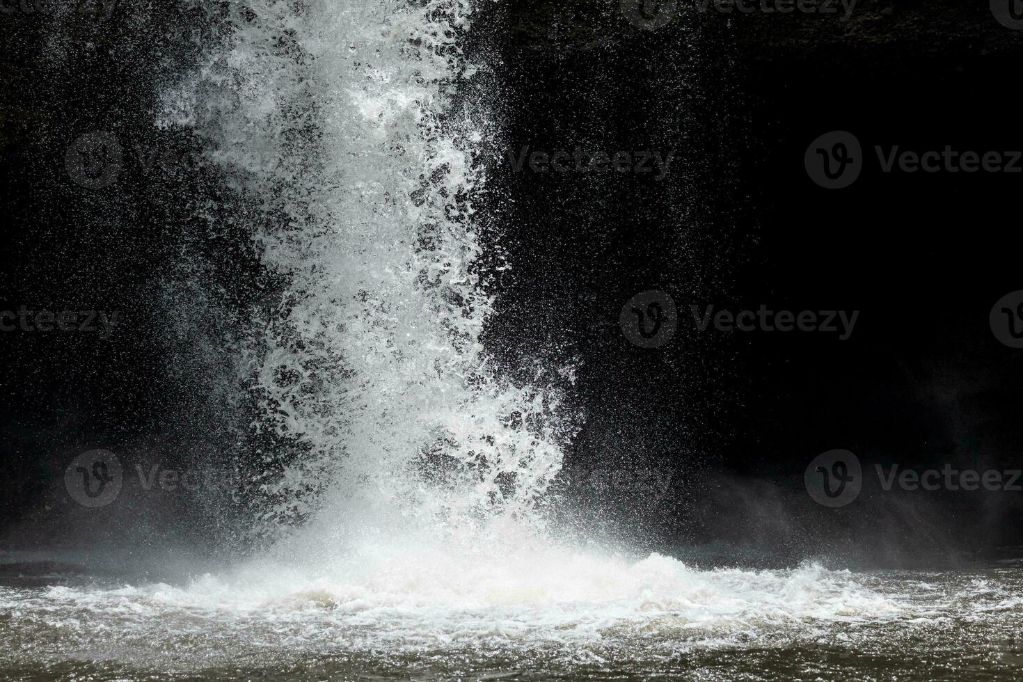 espirrando água a partir de poderoso cascata com Sombrio fundo. foto