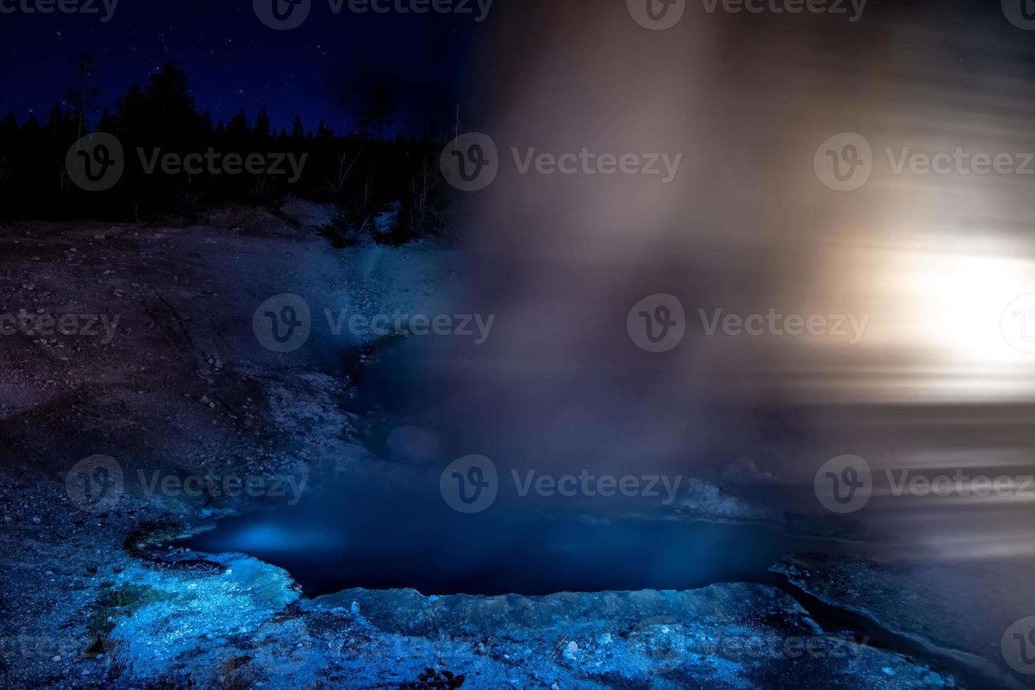 gêiseres de Yellowstone em erupção à noite iluminados pela luz foto