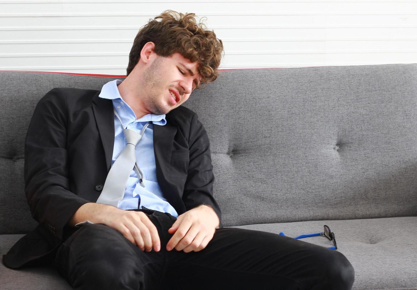 empresário demitido do emprego senta-se tristemente no sofá, deprimido e estressado por ser demitido foto
