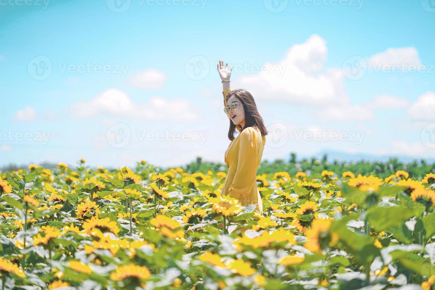 mulher feliz verão despreocupada no campo de girassol na primavera. Mulher asiática multirracial alegre sorrindo com os braços levantados foto