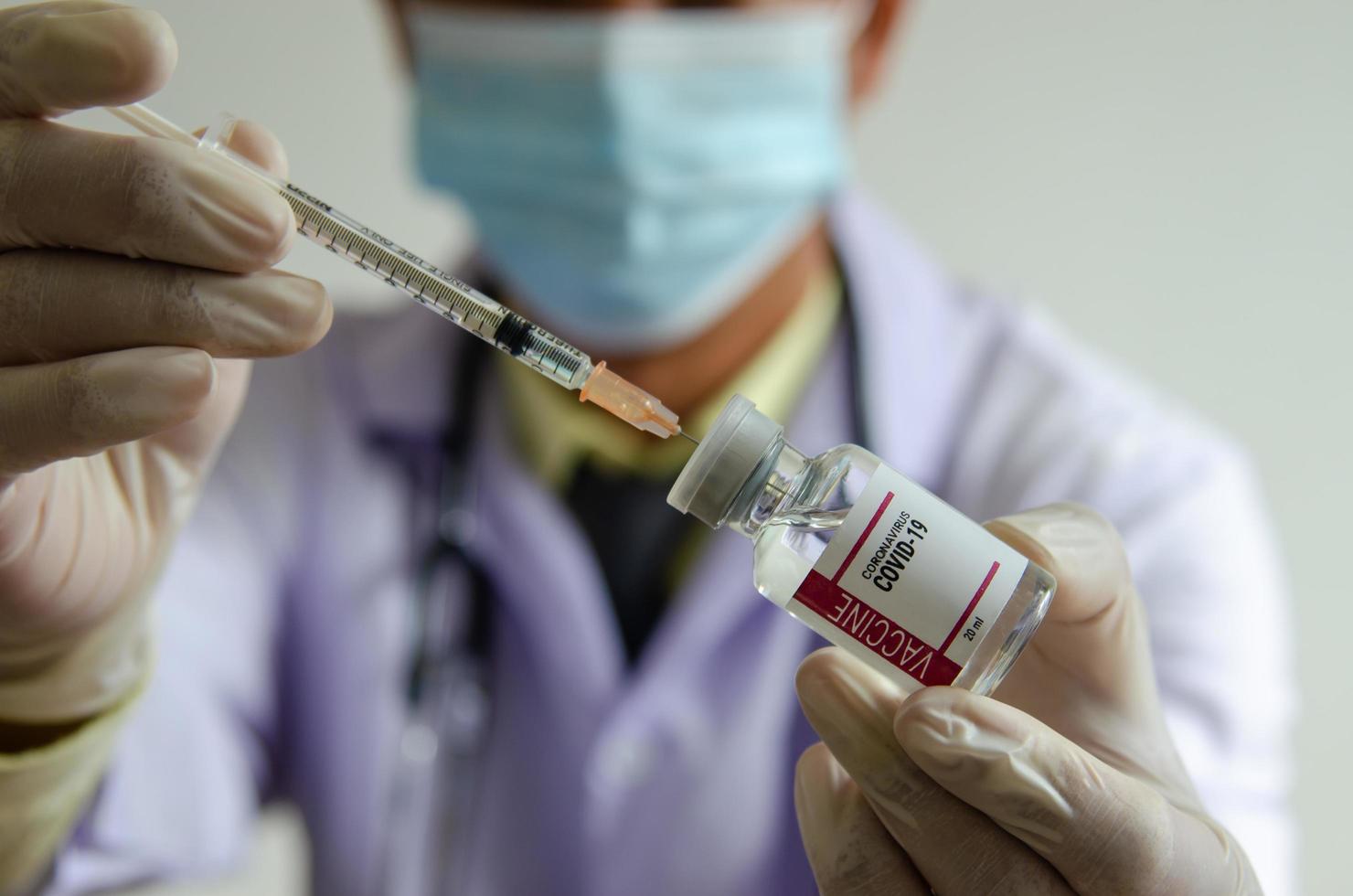 O médico de luvas segurava a seringa e o frasco da vacina. vacina contra coronavírus ou covid-19 foto