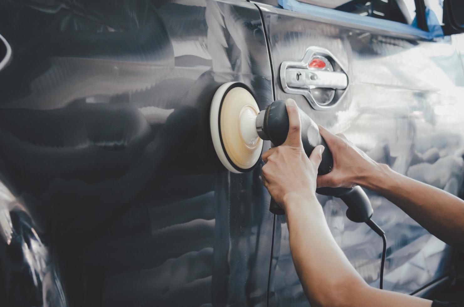 detalhamento de carro - homem trabalhando no polimento e cuidando do exterior com cera. polimento automático com máquina foto