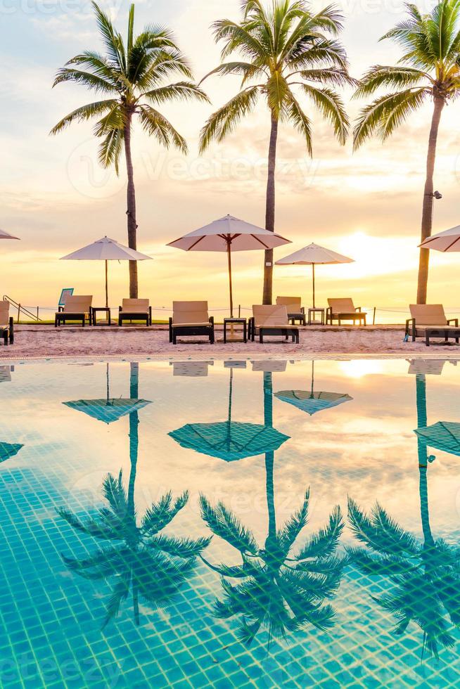 guarda-chuva e cadeira ao redor da piscina em hotel resort com nascer do sol pela manhã foto