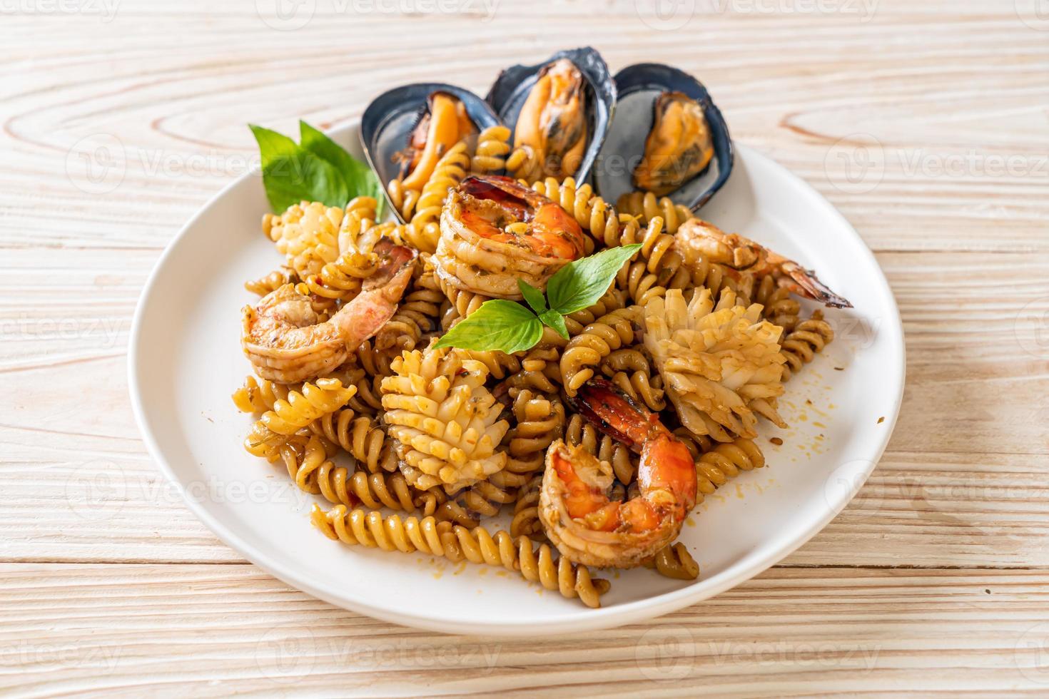 macarrão espiral frito com frutos do mar e molho de manjericão - estilo de comida de fusão foto