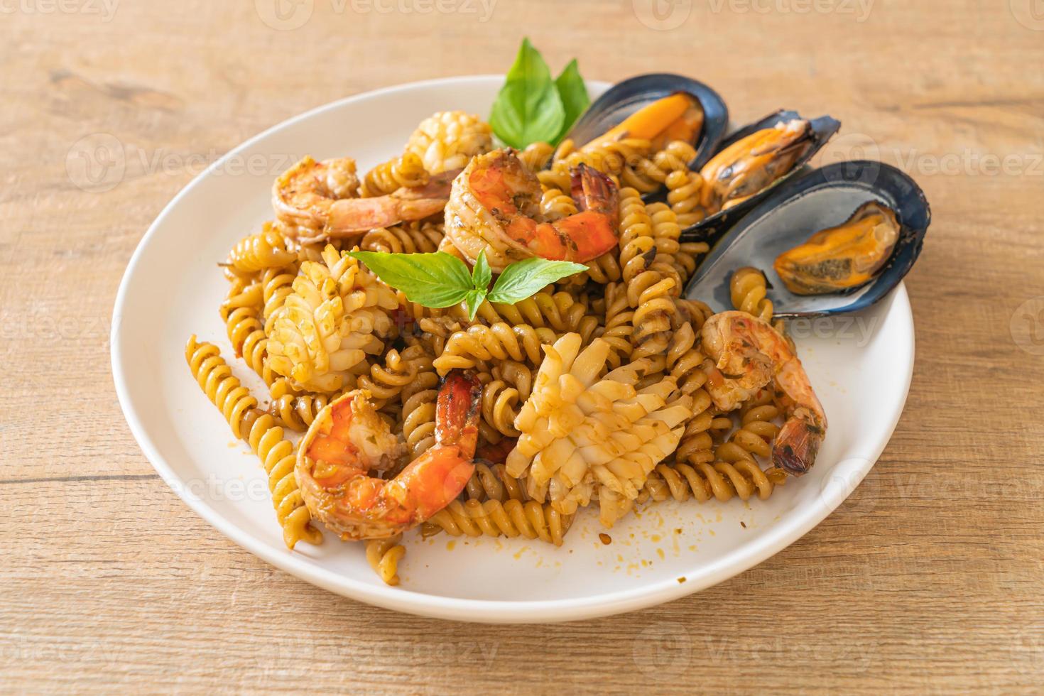 macarrão espiral frito com frutos do mar e molho de manjericão - estilo de comida de fusão foto