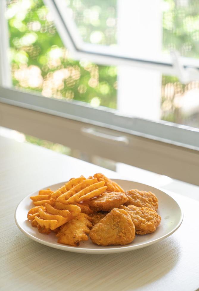 nuggets de frango frito com batatas fritas no prato foto