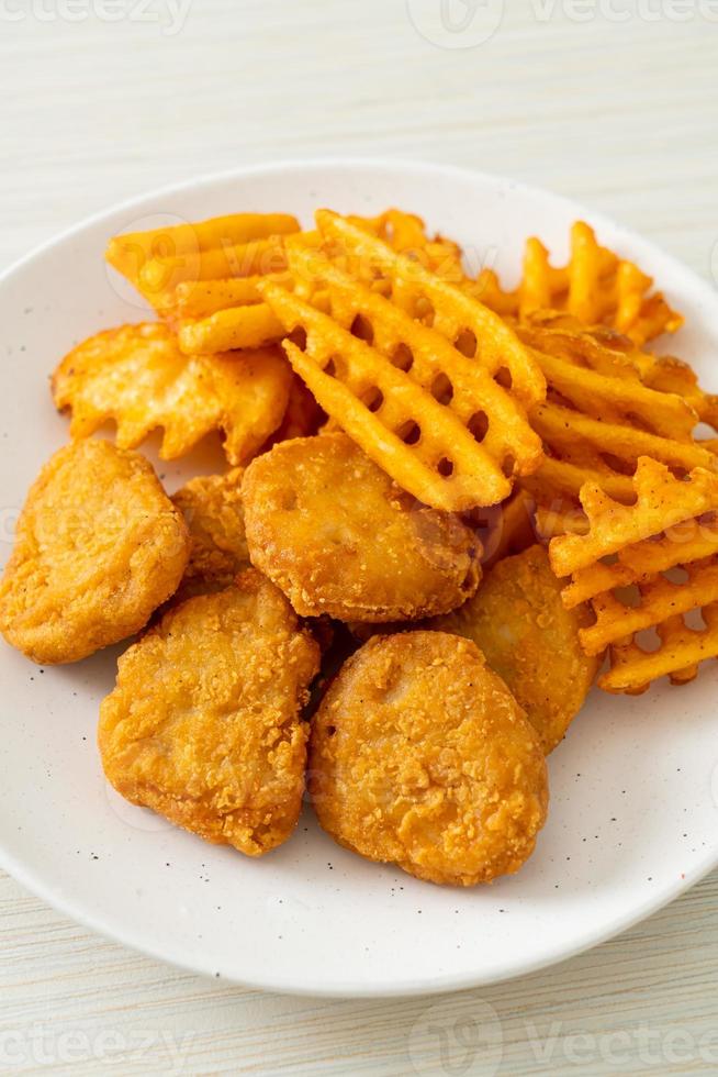 nuggets de frango frito com batatas fritas no prato foto