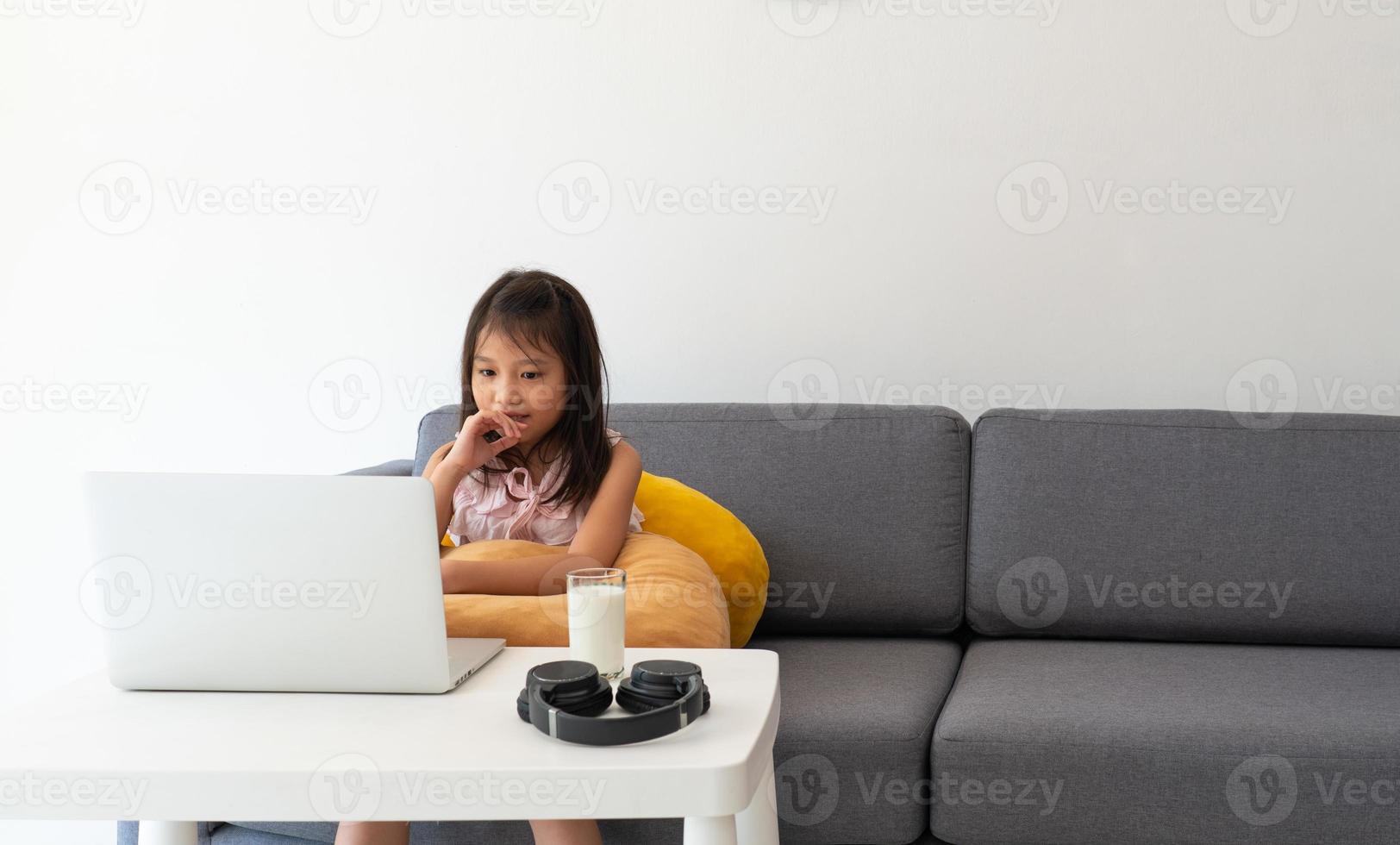 uma jovem asiática usando o computador para leran em casa como protocolo de distanciamento social durante covid-19 ou pandemia de coronavírus. conceito de ensino em casa foto