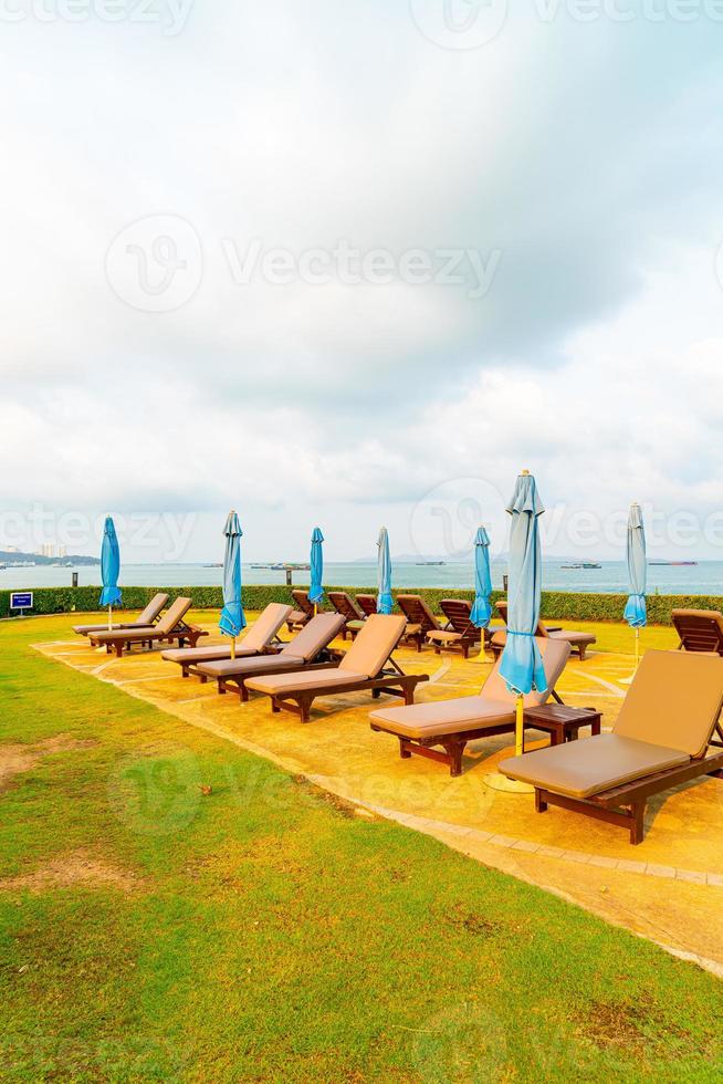 Piscina com cadeiras ou piscina com cama e guarda-sol ao redor da piscina com fundo de praia do mar em Pattaya, na Tailândia foto