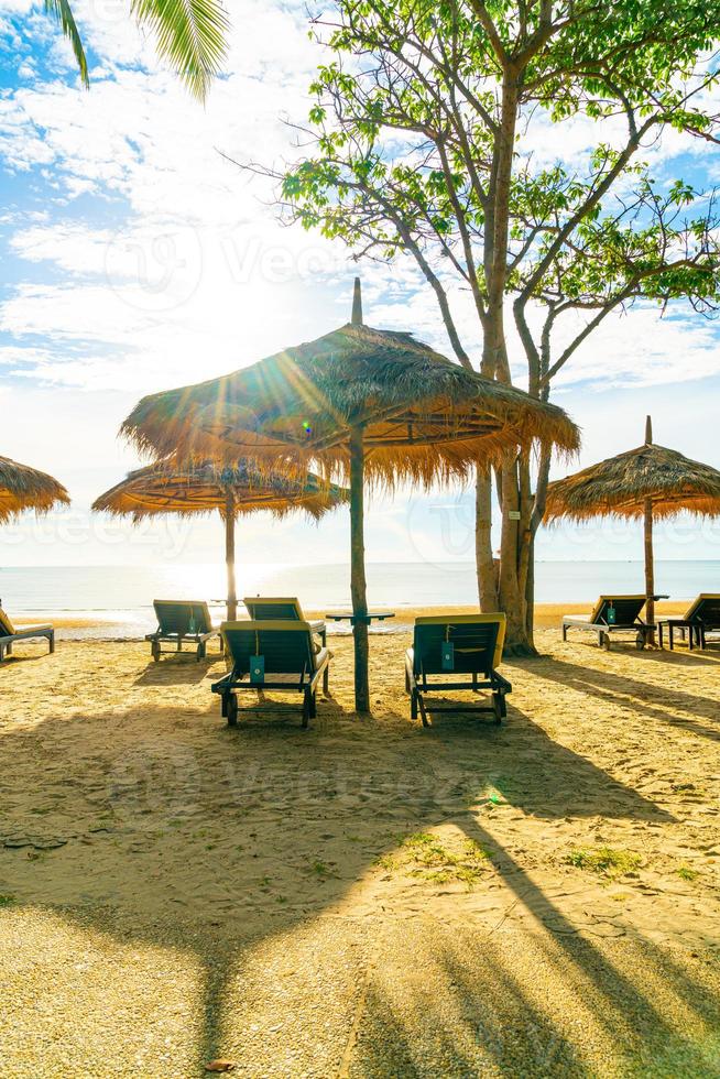 guarda-sóis e cadeiras de praia com coqueiros e fundo de praia de mar e céu azul - conceito de férias e férias foto