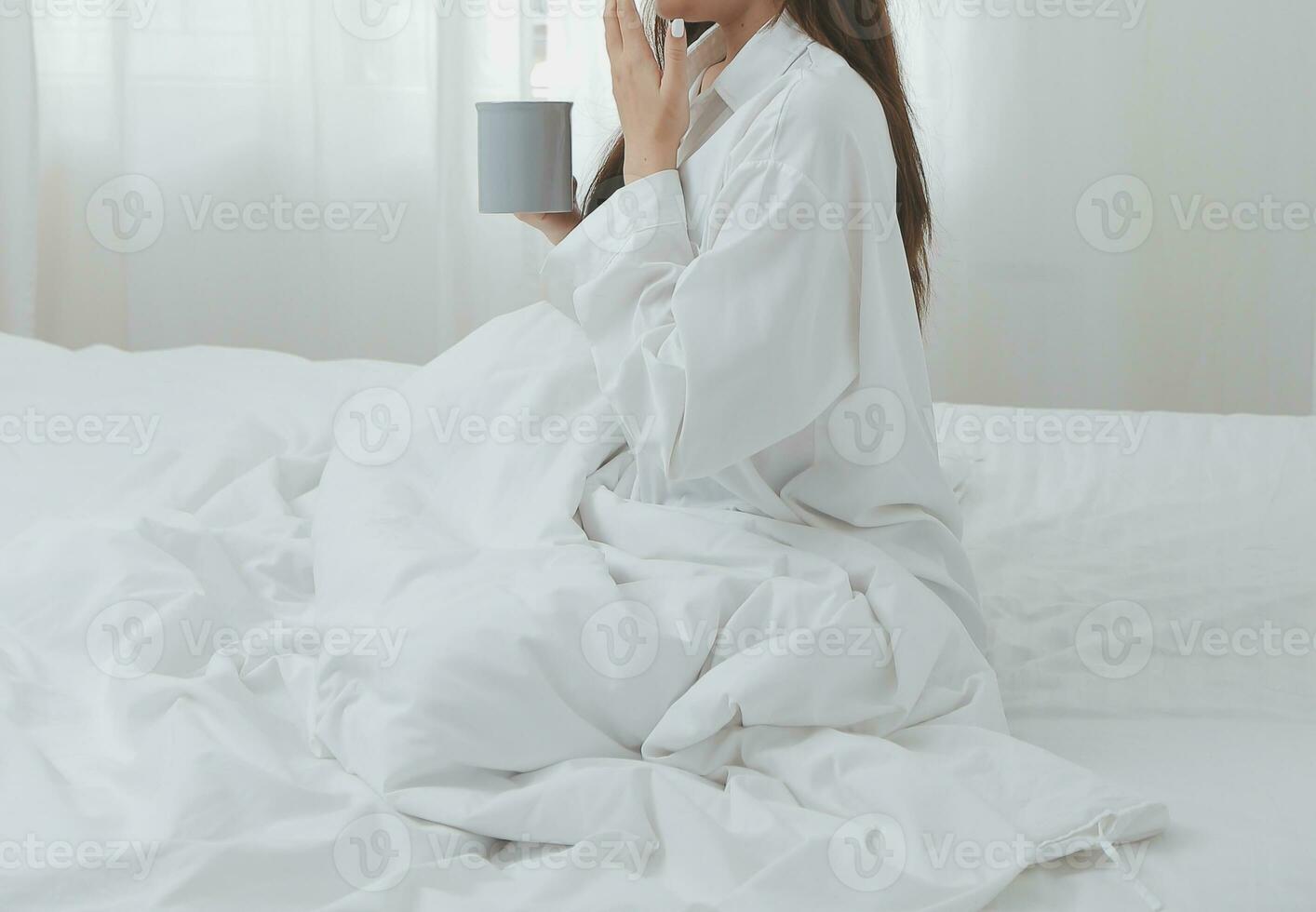 mulher se alongando na cama depois de acordar foto