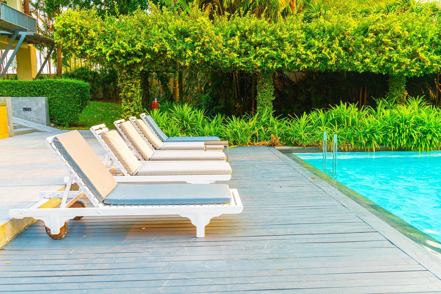 cadeiras de piscina ao redor de piscinas em hotel resort - conceito de feriados e férias foto