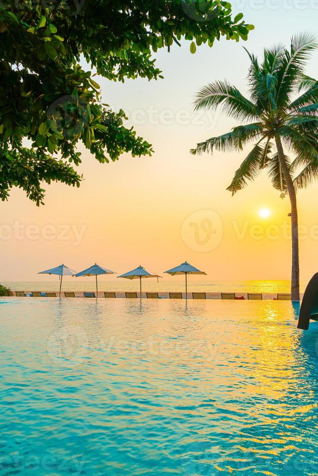 guarda-sol e cadeira ao redor da piscina com vista para o mar foto