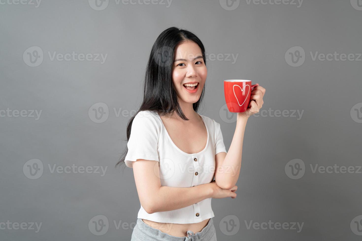 jovem mulher asiática com um rosto feliz e uma mão segurando uma xícara de café foto