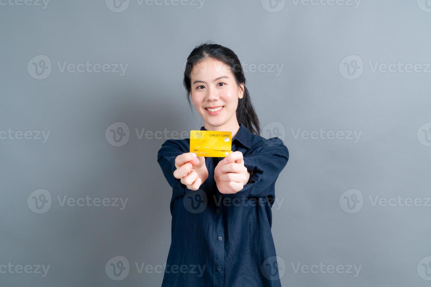 retrato de uma adorável jovem asiática mostrando cartão de crédito foto