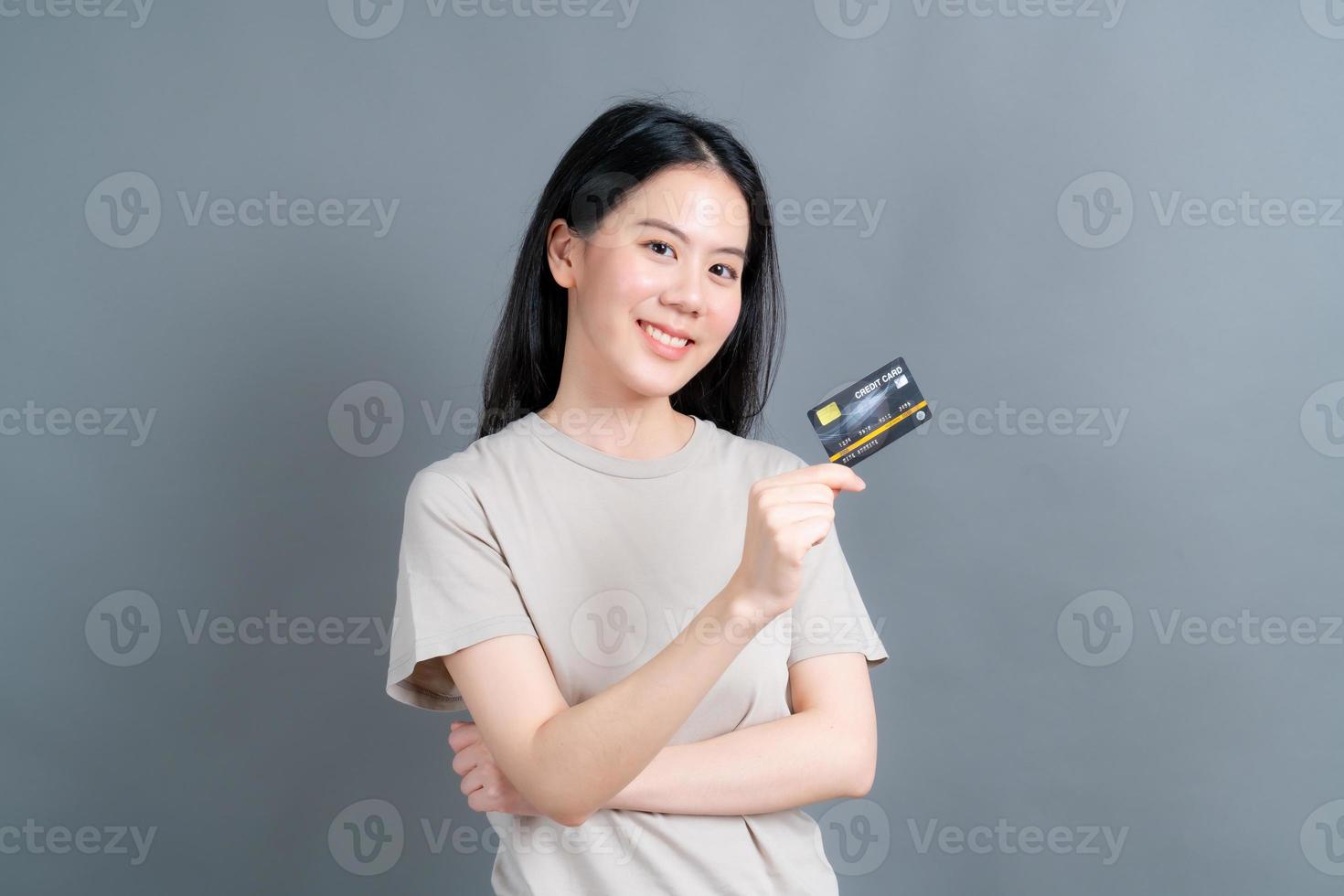retrato de uma adorável jovem asiática mostrando cartão de crédito foto
