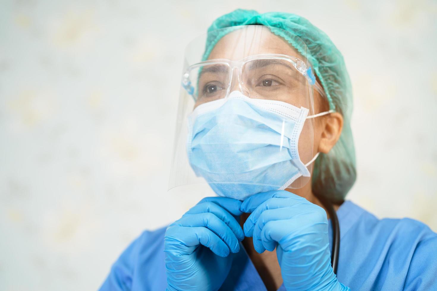 médico asiático usando protetor facial e terno novo normal para verificar o paciente protege a segurança infecção covid-19 surto de coronavírus na enfermaria de quarentena do hospital. foto