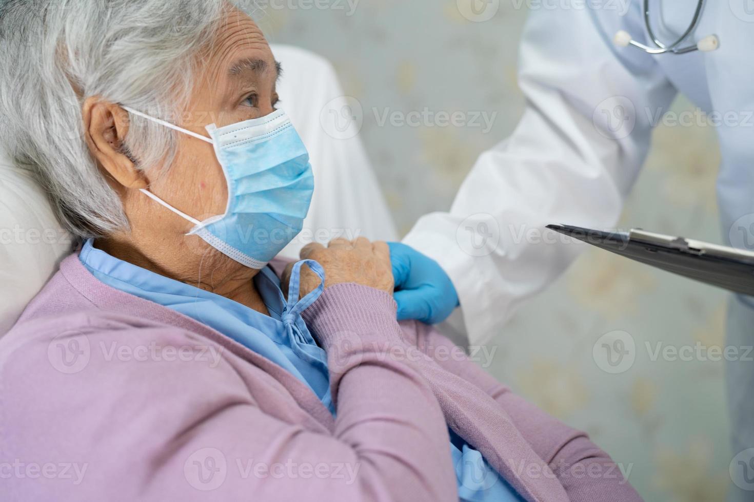 médico usando o estetoscópio para verificar o paciente asiático sênior ou idosa senhora usando uma máscara facial no hospital para proteger a infecção covid-19 coronavírus. foto