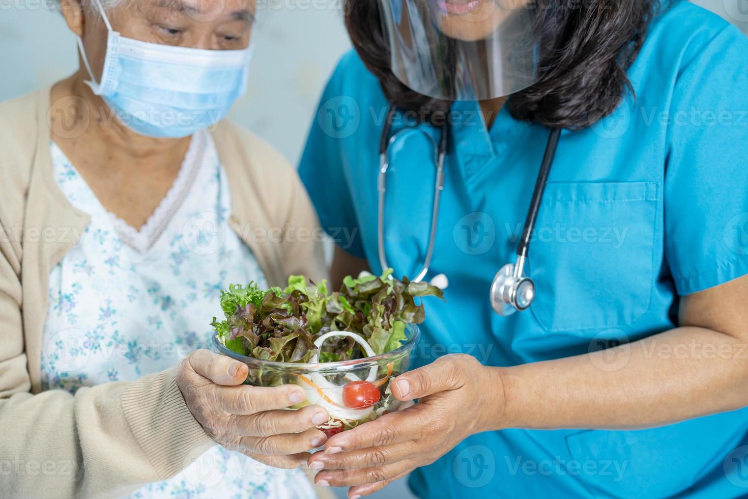 paciente asiático sênior ou idosa idosa comendo alimentos saudáveis de vegetais de café da manhã com esperança e feliz enquanto está sentado e com fome na cama no hospital. foto