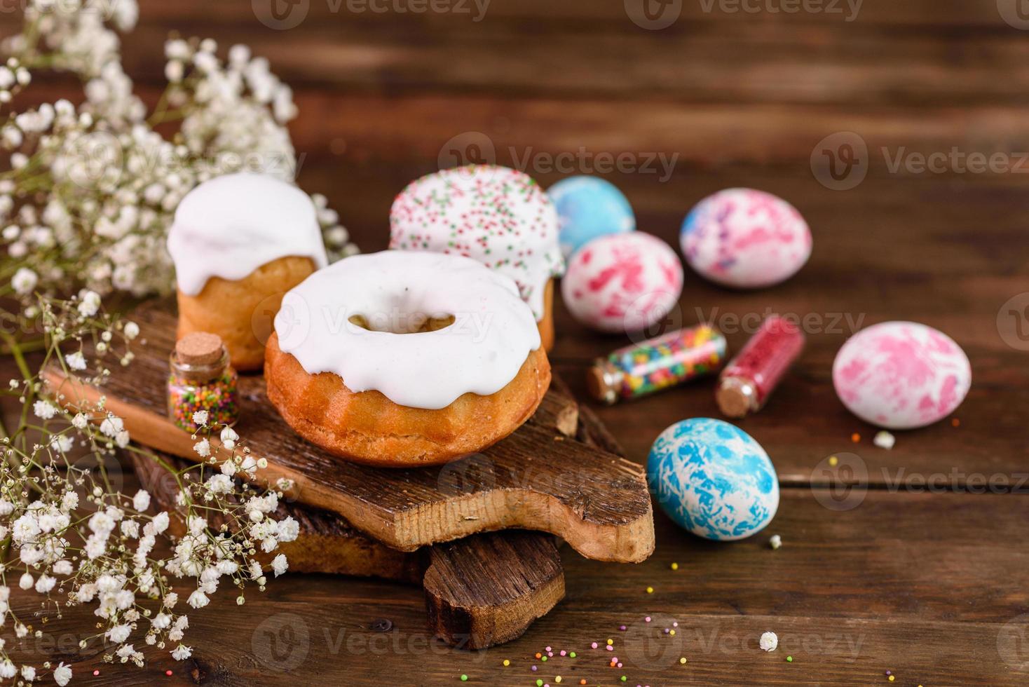 Bolos festivos com esmalte branco, nozes e passas com ovos de páscoa na mesa festiva foto