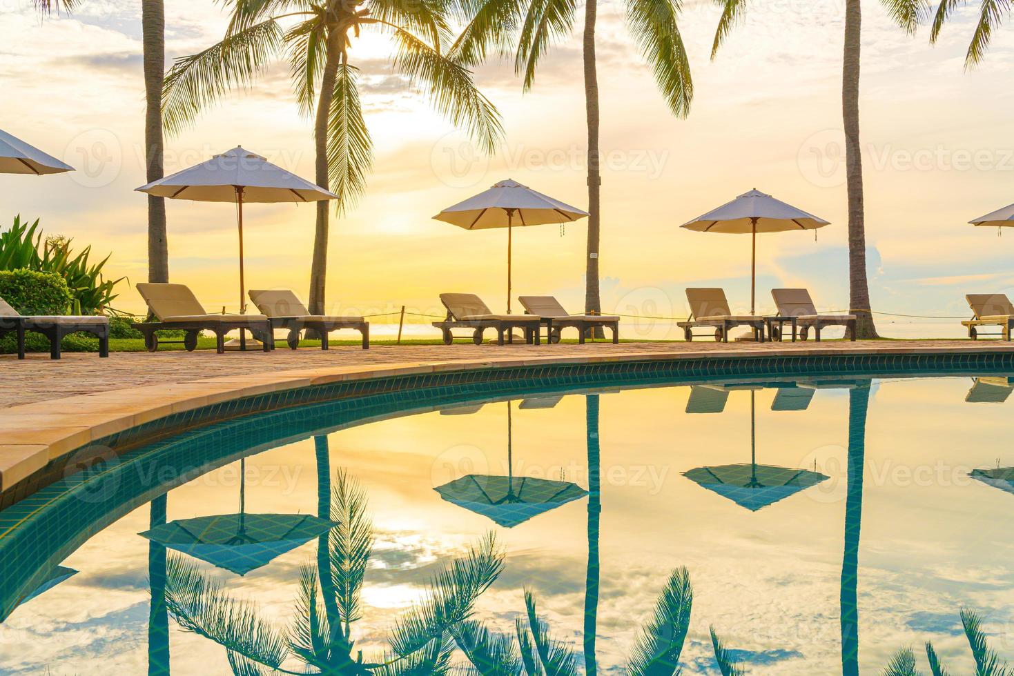 guarda-sol e cadeira ao redor da piscina em hotel resort para viagens de lazer e férias perto da praia do mar foto