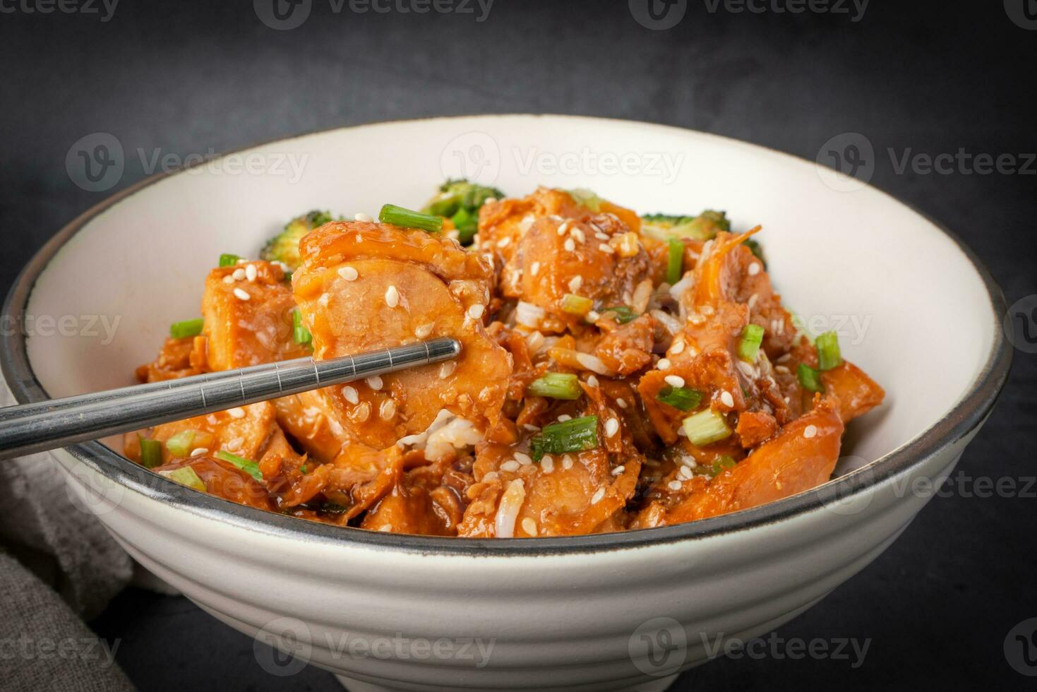 pauzinhos com delicioso doce cortar frango arroz, sésamo sementes, fatiado Primavera cebolas, brócolis, e legumes. ásia comida, japonês Comida. fechar acima foto