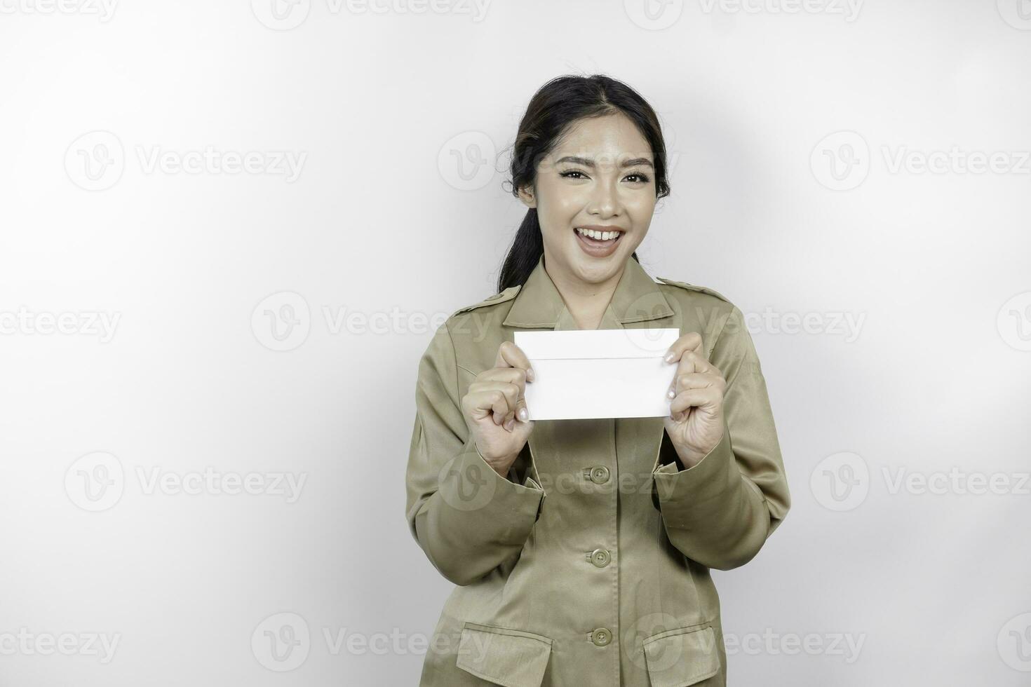 uma feliz jovem lindo ásia trabalhador vestindo Castanho uniforme segurando a envelope. indonésio pns conceito. foto