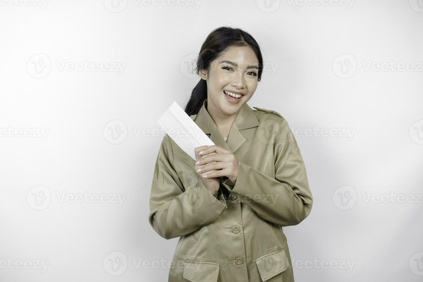 uma feliz jovem lindo ásia trabalhador vestindo Castanho uniforme segurando a envelope. indonésio pns conceito. foto