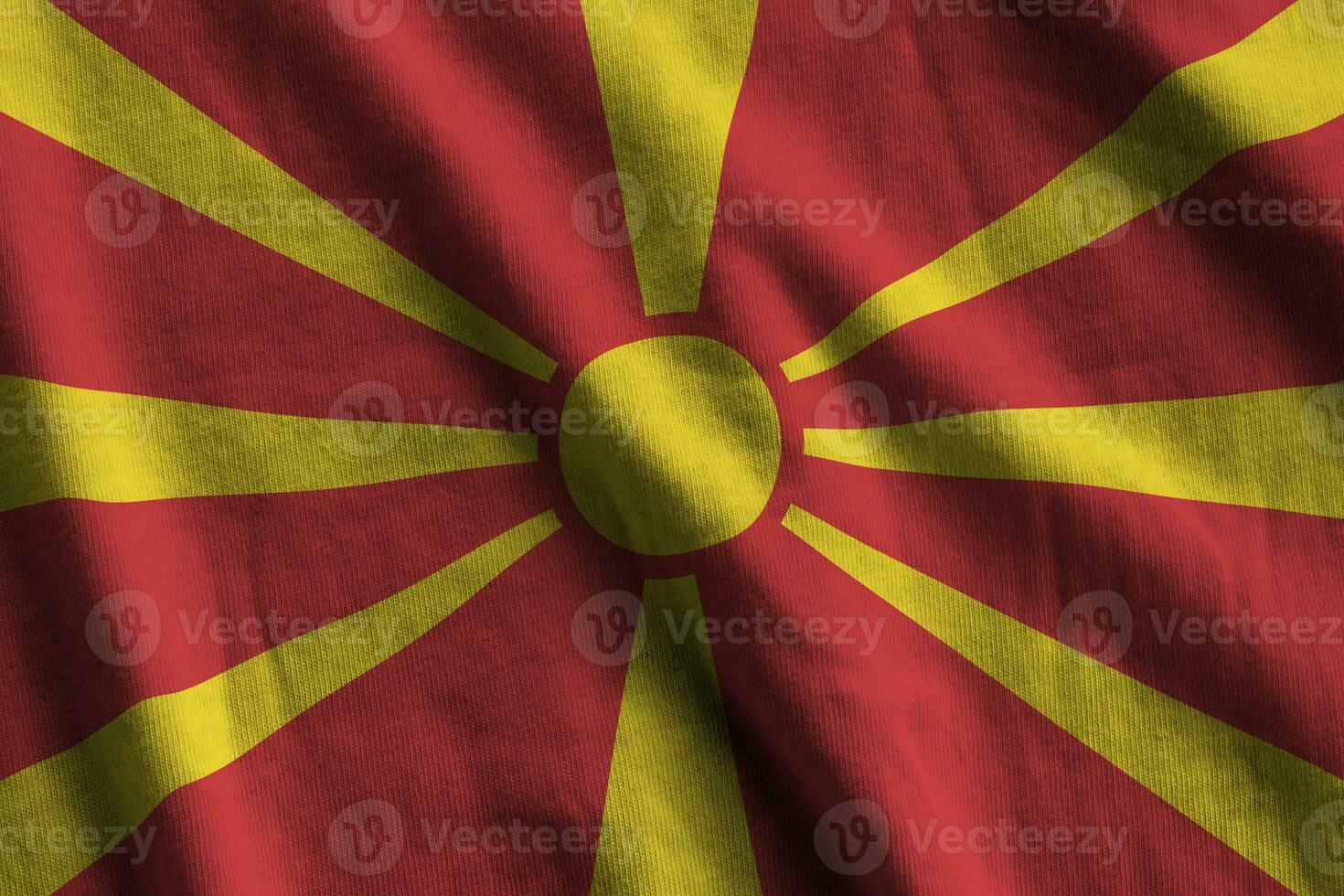 bandeira da macedônia com grandes dobras acenando de perto sob a luz do estúdio dentro de casa. os símbolos oficiais e cores no banner foto