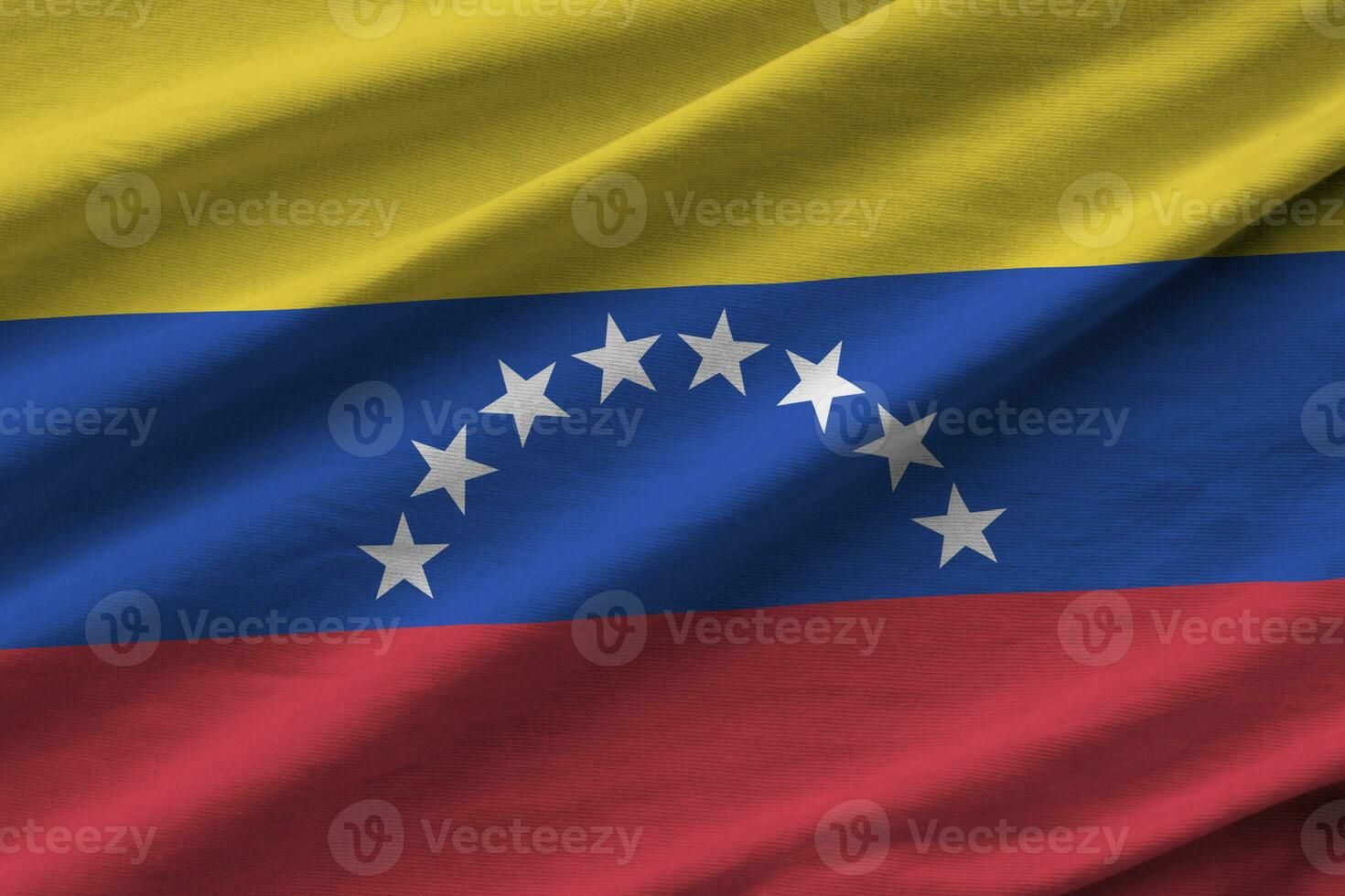 bandeira da venezuela com grandes dobras acenando de perto sob a luz do estúdio dentro de casa. os símbolos oficiais e cores no banner foto