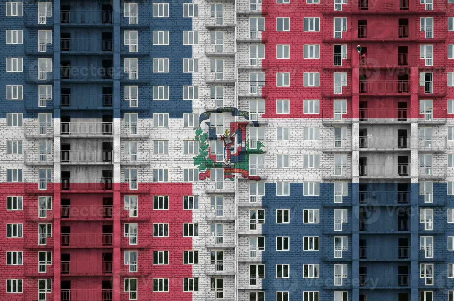 dominicano república bandeira retratado dentro pintura cores em de vários andares residente construção debaixo construção. texturizado bandeira em tijolo parede fundo foto