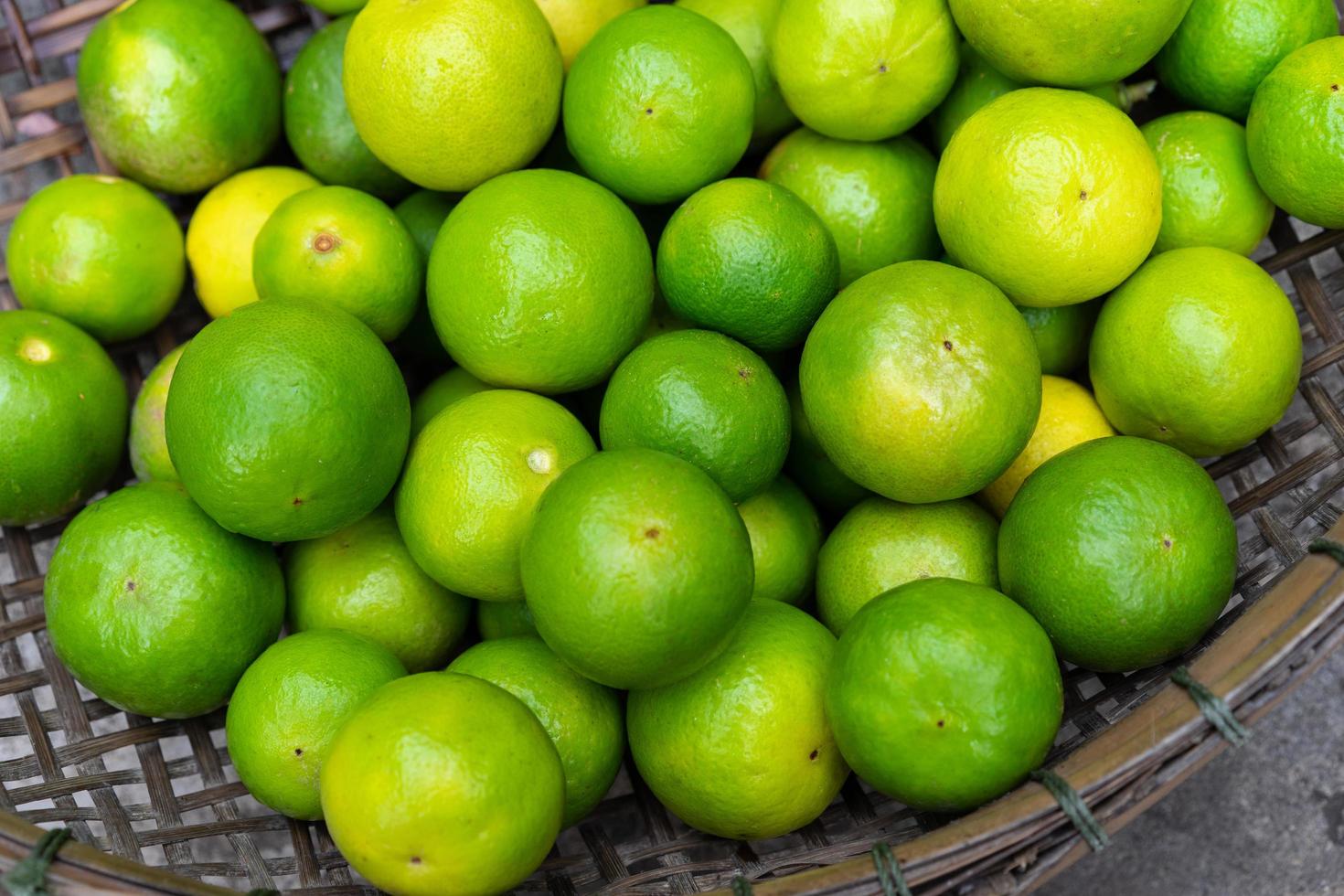 limas verdes frescas em uma cesta de madeira para vender no mercado foto