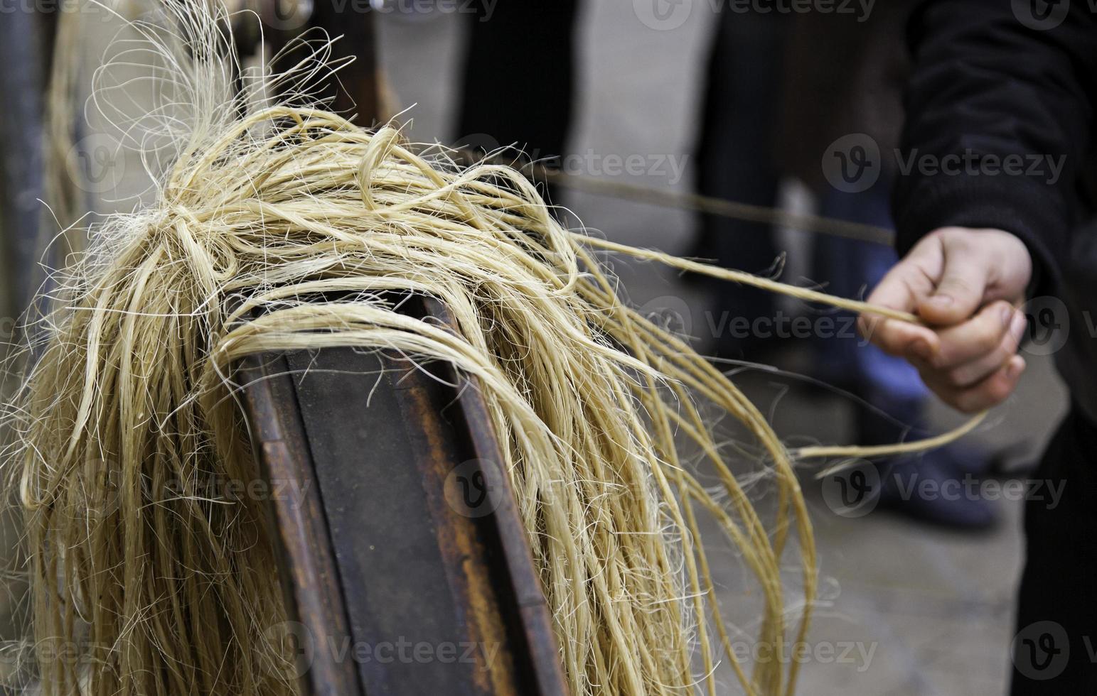 artesão torcendo corda de esparto com as mãos foto