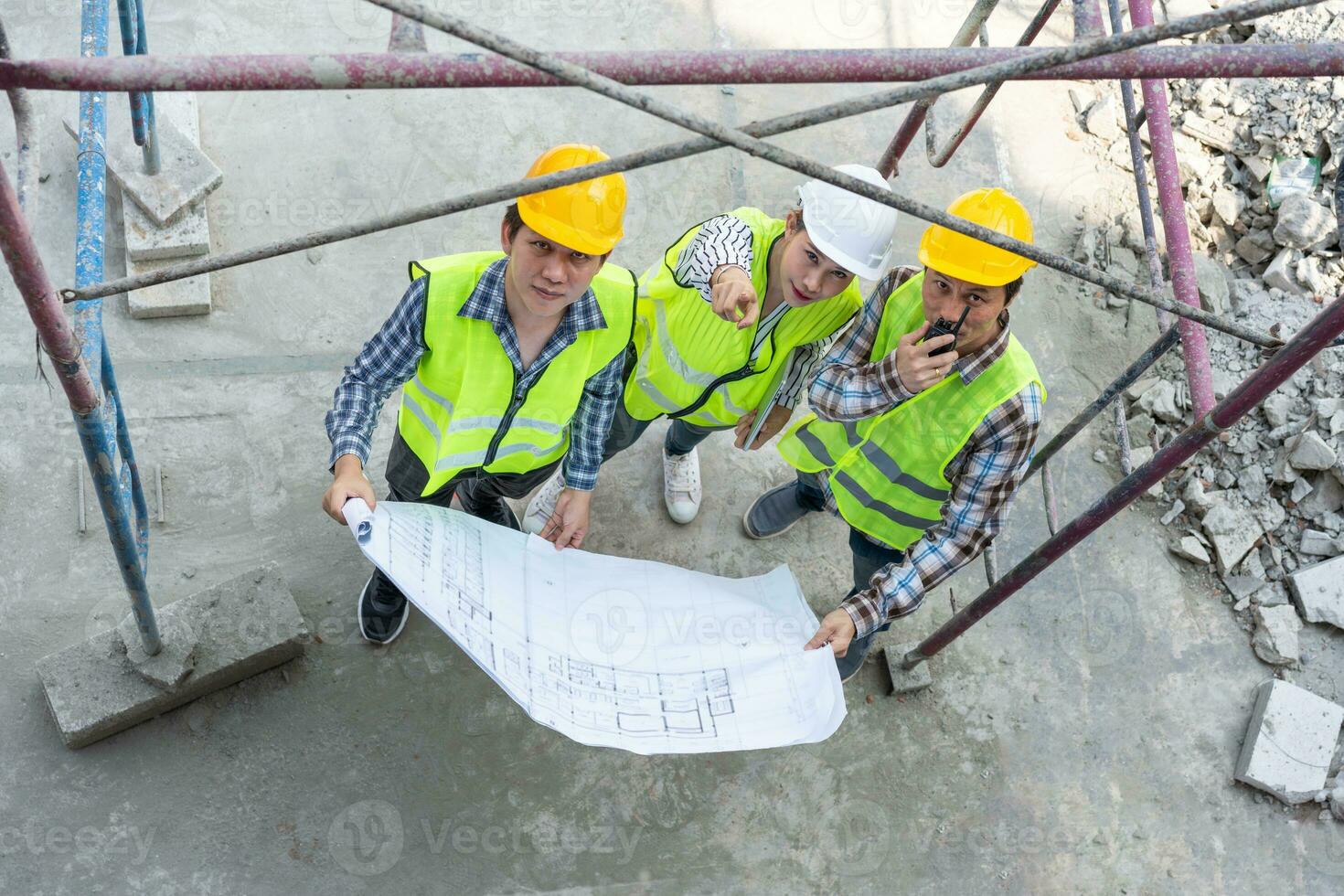 visão superior do engenheiro asiático ou jovem arquiteto feminino colocar um capacete para segurança e conversar com um empreiteiro em um projeto de fábrica de construção civil, conceito de trabalho em equipe, conceito de liderança. foto