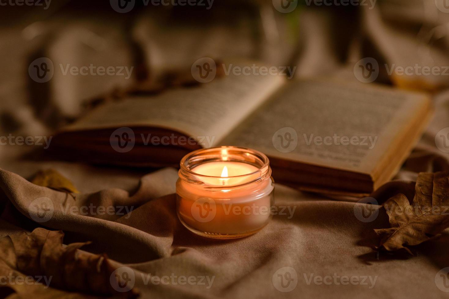 uma vela acesa em uma mesa de madeira em frente a um livro a meio mastro foto