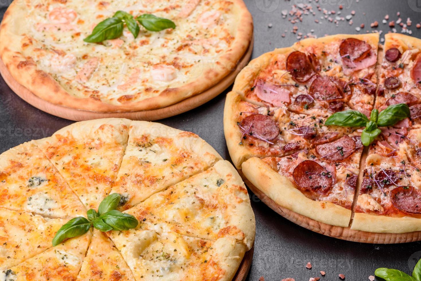 deliciosa pizza fresca de forno com tomate, salame e bacon em um fundo escuro de concreto foto