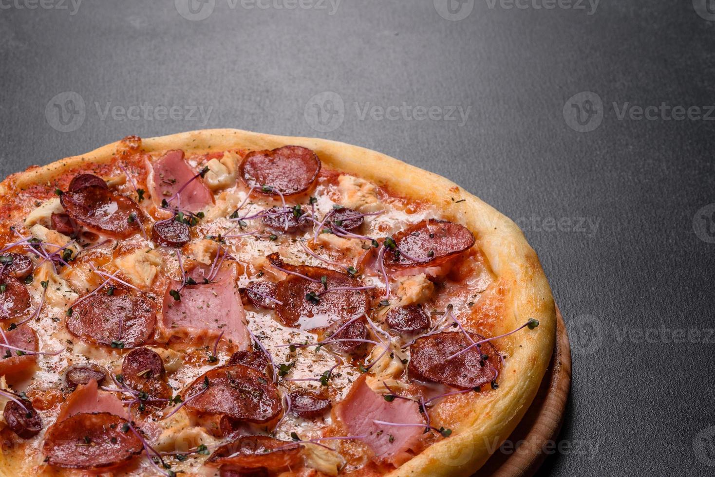 deliciosa pizza fresca de forno com tomate, salame e bacon em um fundo escuro de concreto foto