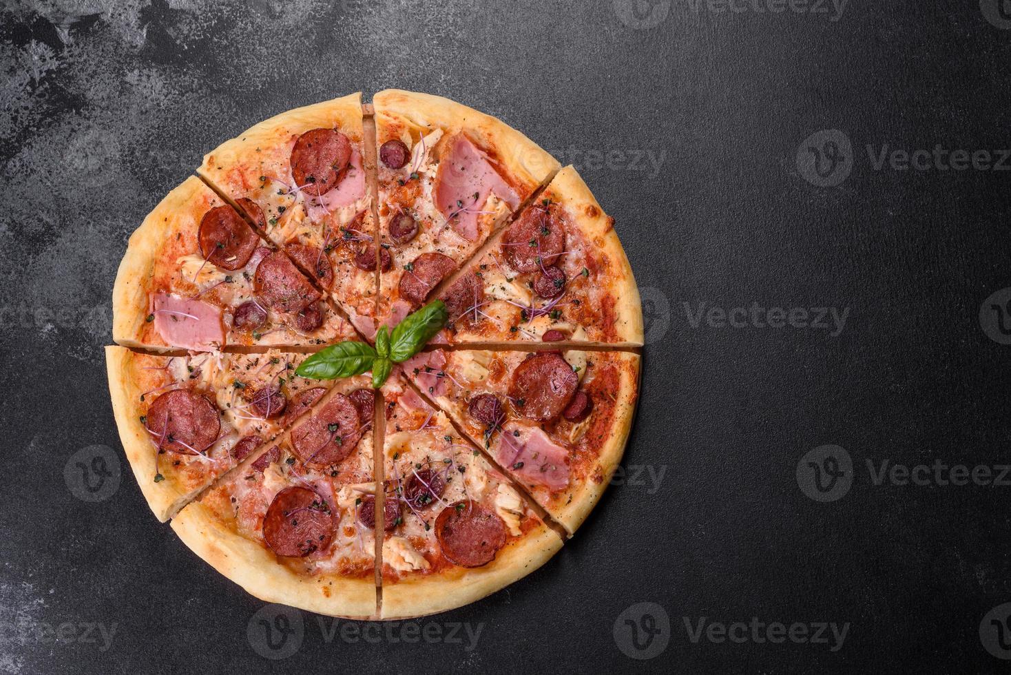 deliciosa pizza fresca de forno com tomate, salame e bacon em um fundo escuro de concreto foto