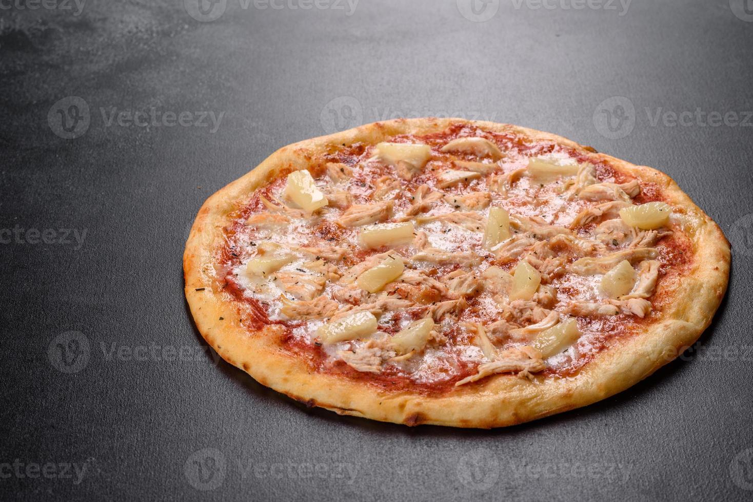 saborosa pizza fresca de forno com tomate, queijo e abacaxi em um fundo escuro de concreto foto