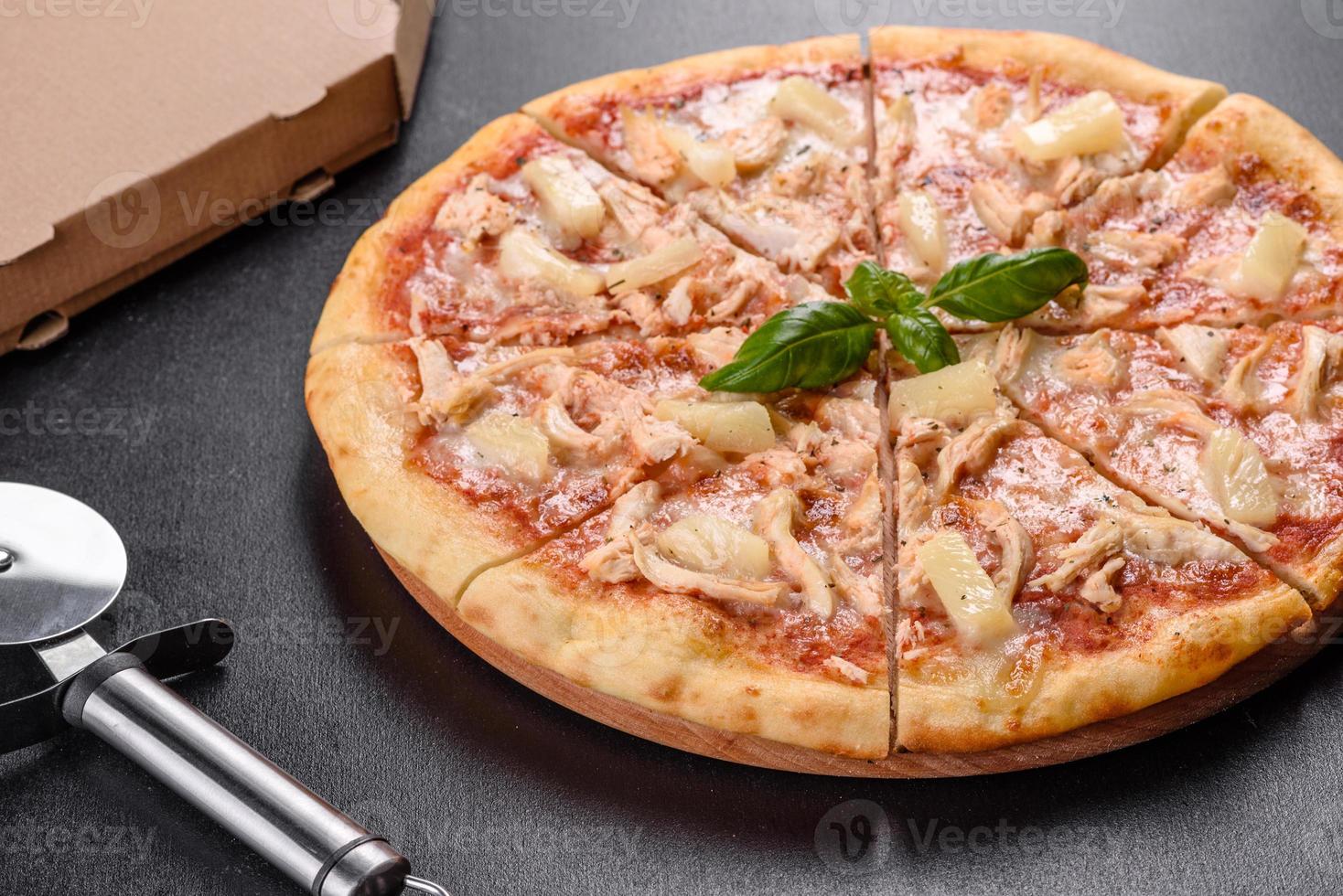 saborosa pizza fresca de forno com tomate, queijo e abacaxi em um fundo escuro de concreto foto
