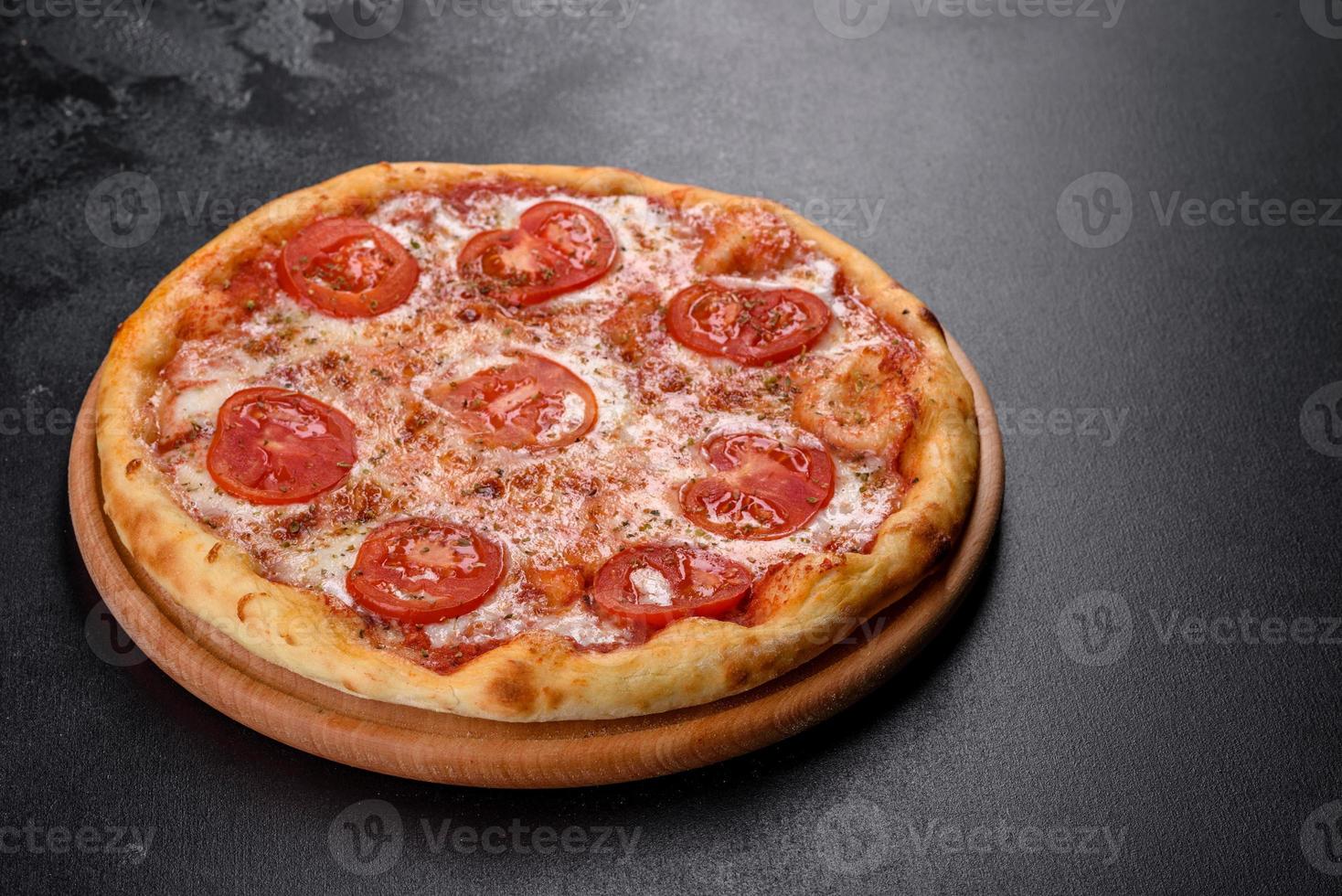 saborosa pizza fresca de forno com tomate, queijo e manjericão em um fundo de concreto foto