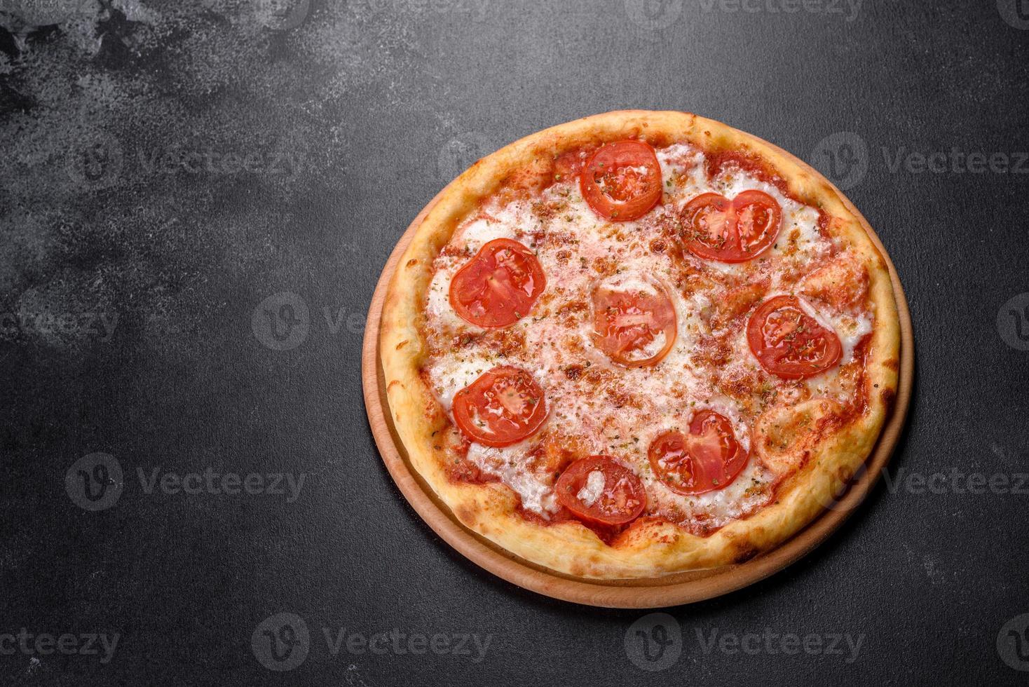 saborosa pizza fresca de forno com tomate, queijo e manjericão em um fundo de concreto foto