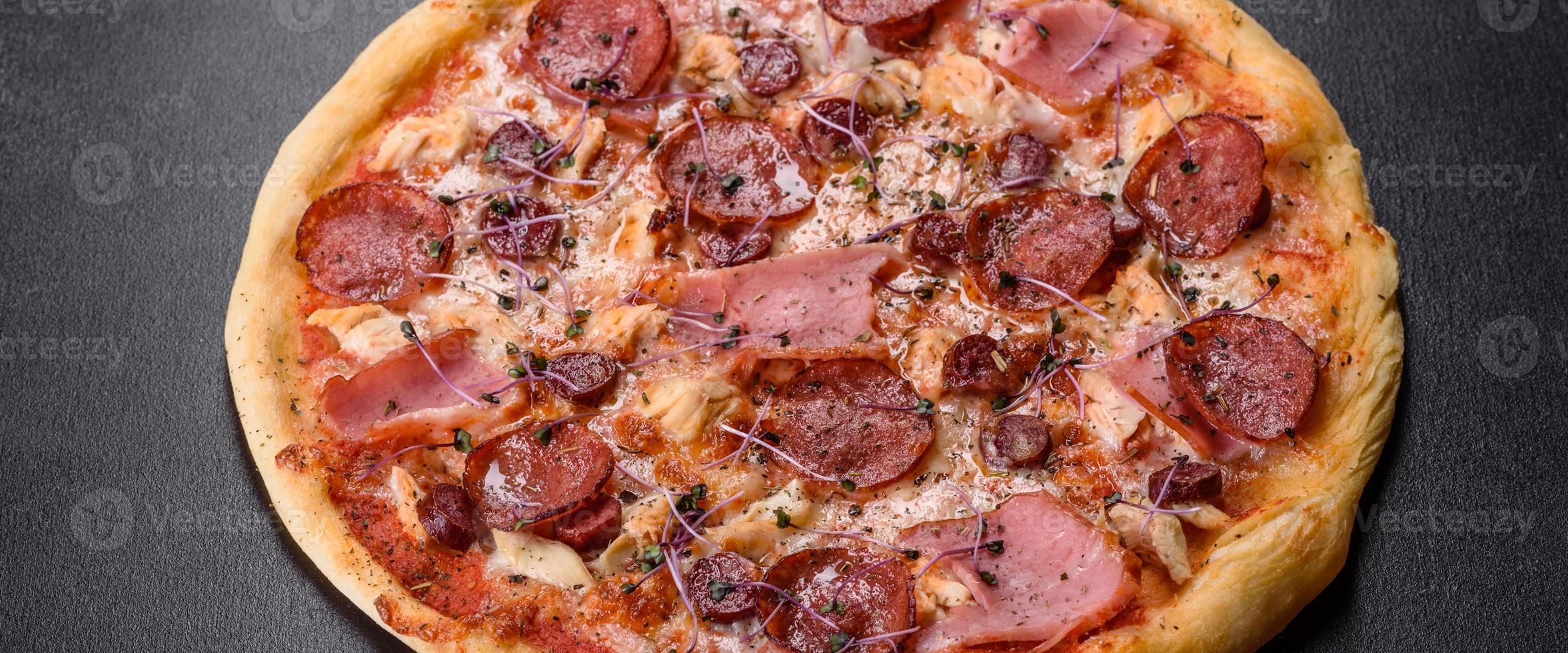 deliciosa pizza fresca de forno com tomate, salame e bacon em um fundo escuro de concreto foto