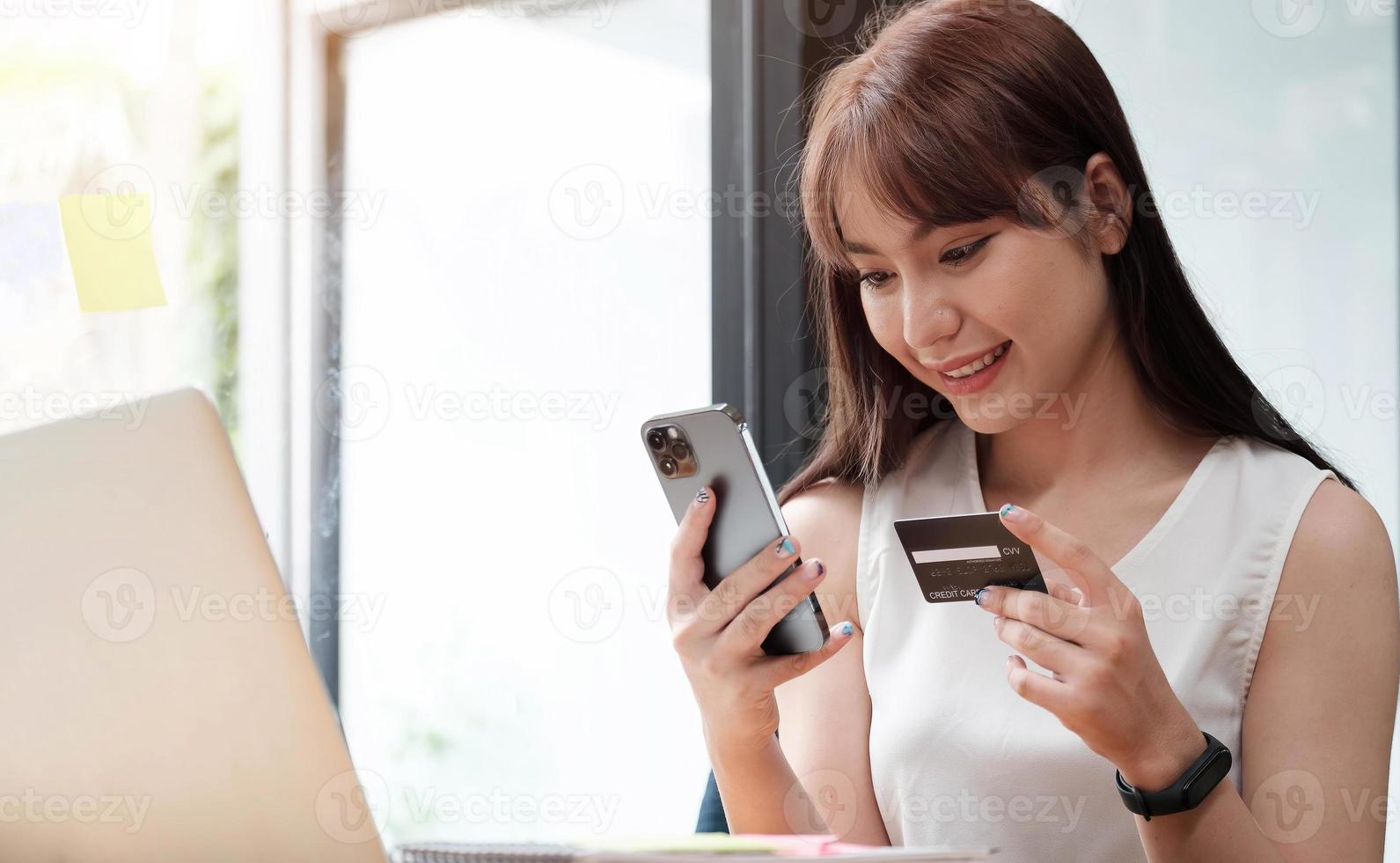 retrato de uma mulher feliz comprando online com um telefone inteligente no escritório. foto