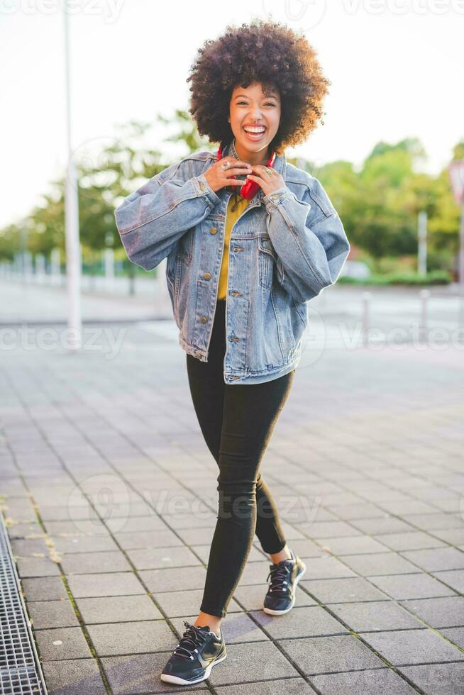 retrato do feliz jovem mulher com afro penteado dentro a cidade foto