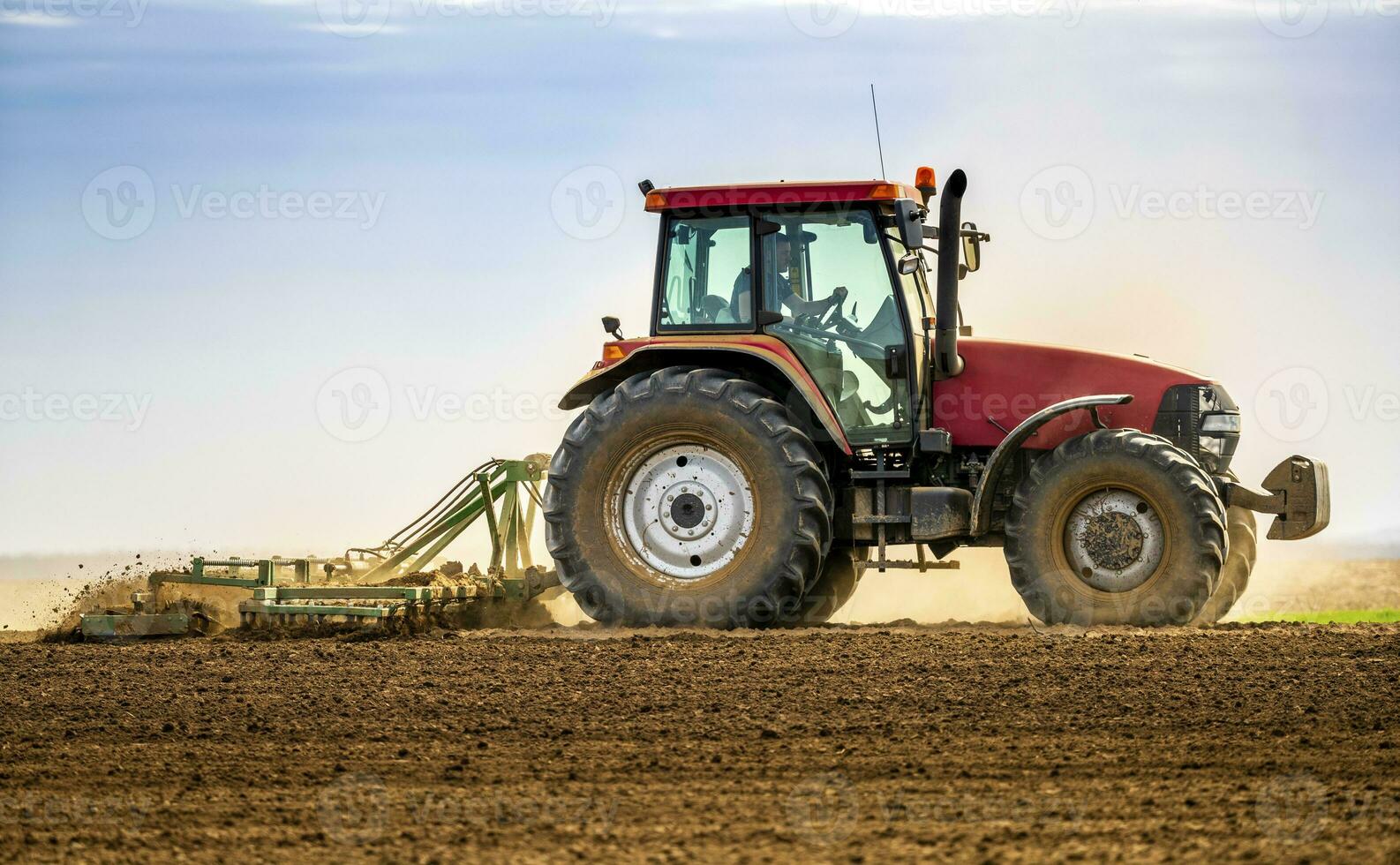 agricultor dentro trator aração campo dentro Primavera foto