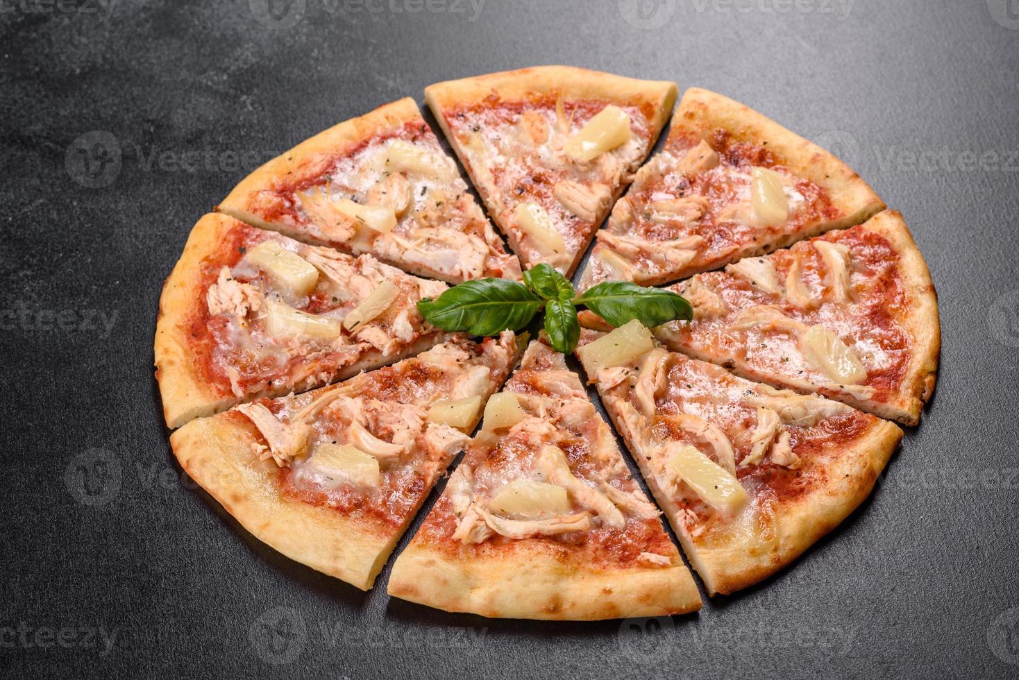 saborosa pizza fresca de forno com tomate, queijo e abacaxi em um fundo escuro de concreto foto