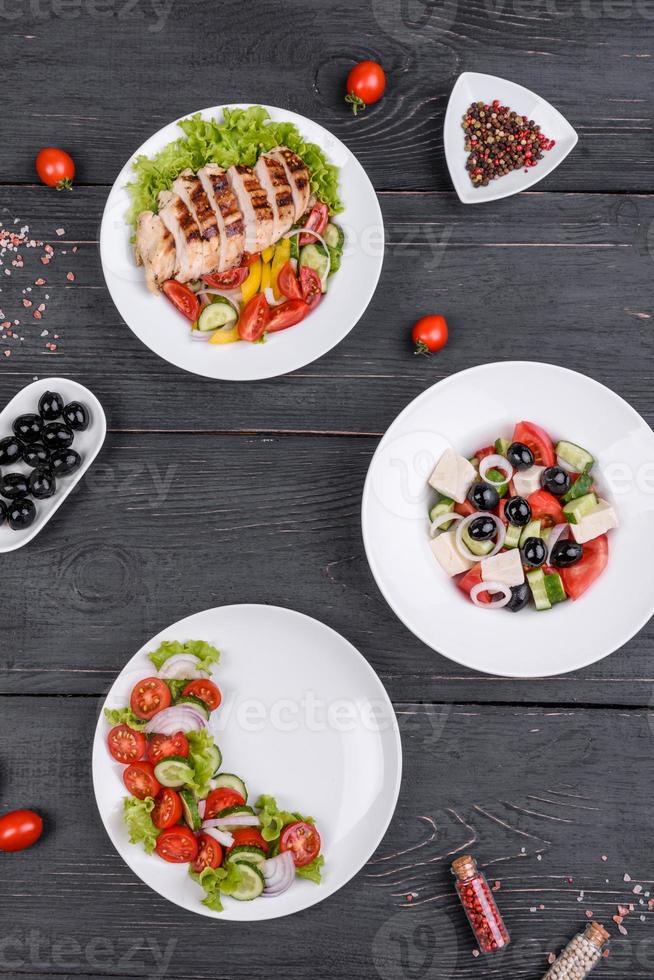 três deliciosas saladas frescas com frango, tomate, pepino, cebola e verduras com azeite de oliva foto